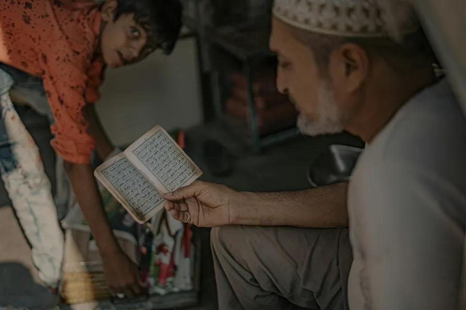 أب مسلم يجلس مع ابنه الصغير ويتحدثان بهدوء في البيت