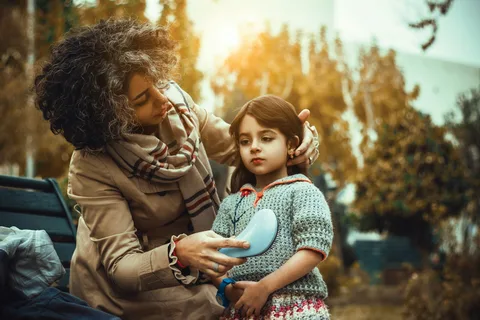 طفل صغير أمام رفوف الحلوى في متجر وأمه تمسك بيده